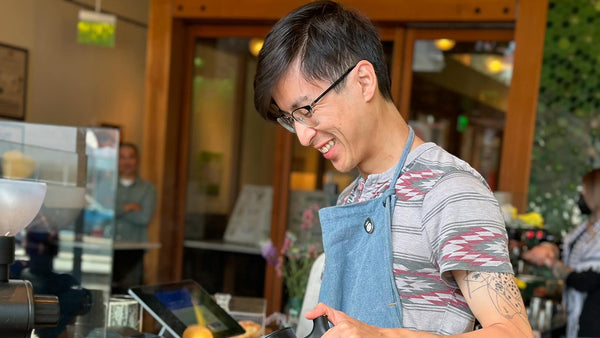Tim pouring coffee into a pour-over device in a coffee shop.