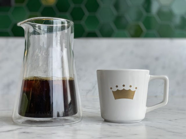brewed coffee in a carafe and a mug with The Crown logo on it
